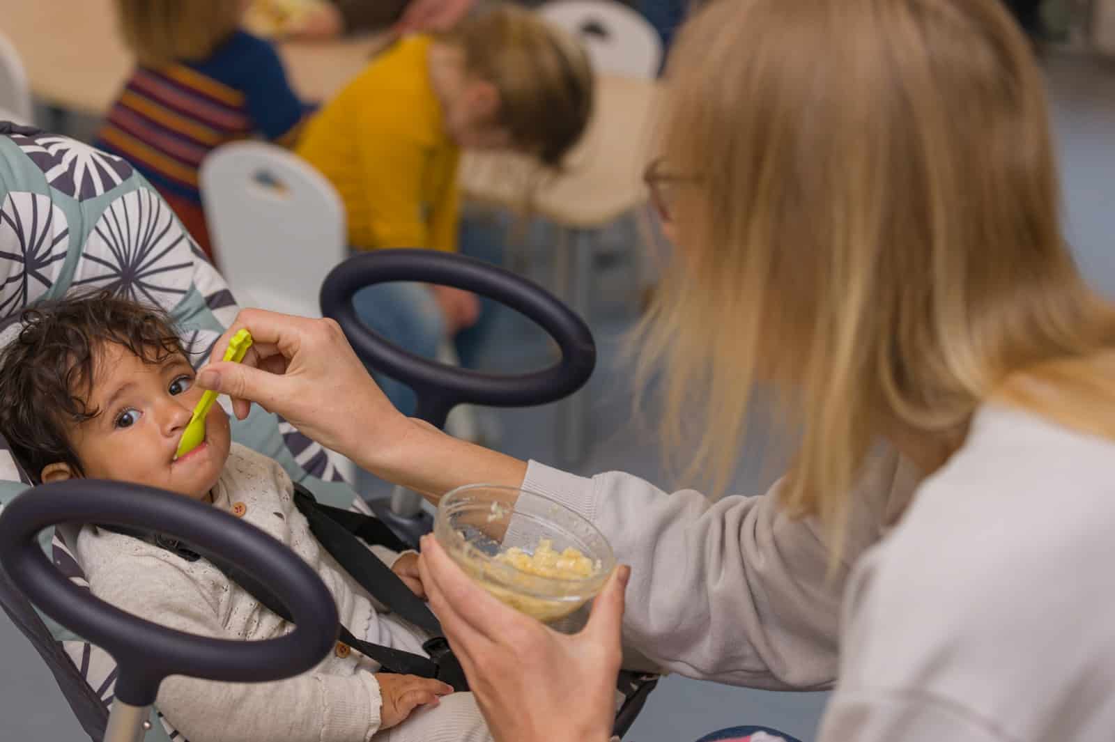 Pedagogisch medewerker geeft een baby een gezonde maaltijd bij Winja Wanja